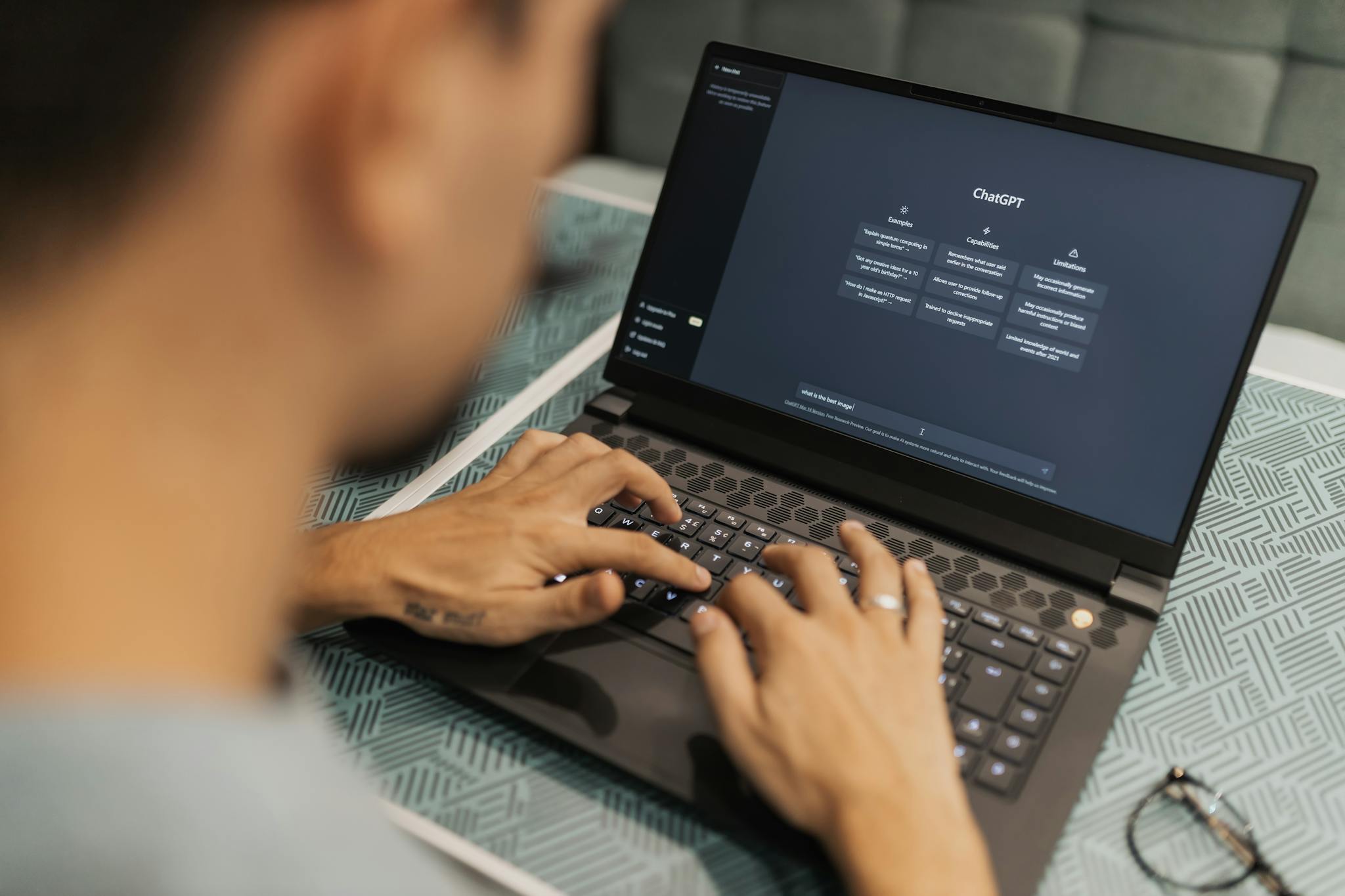 A focused individual types on a laptop running AI software indoors.